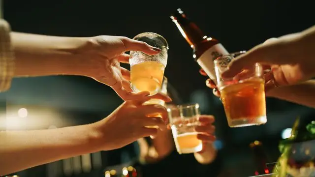 Un grupo de personas brinda con bebidas alcohólicas durante una reunión social nocturna.